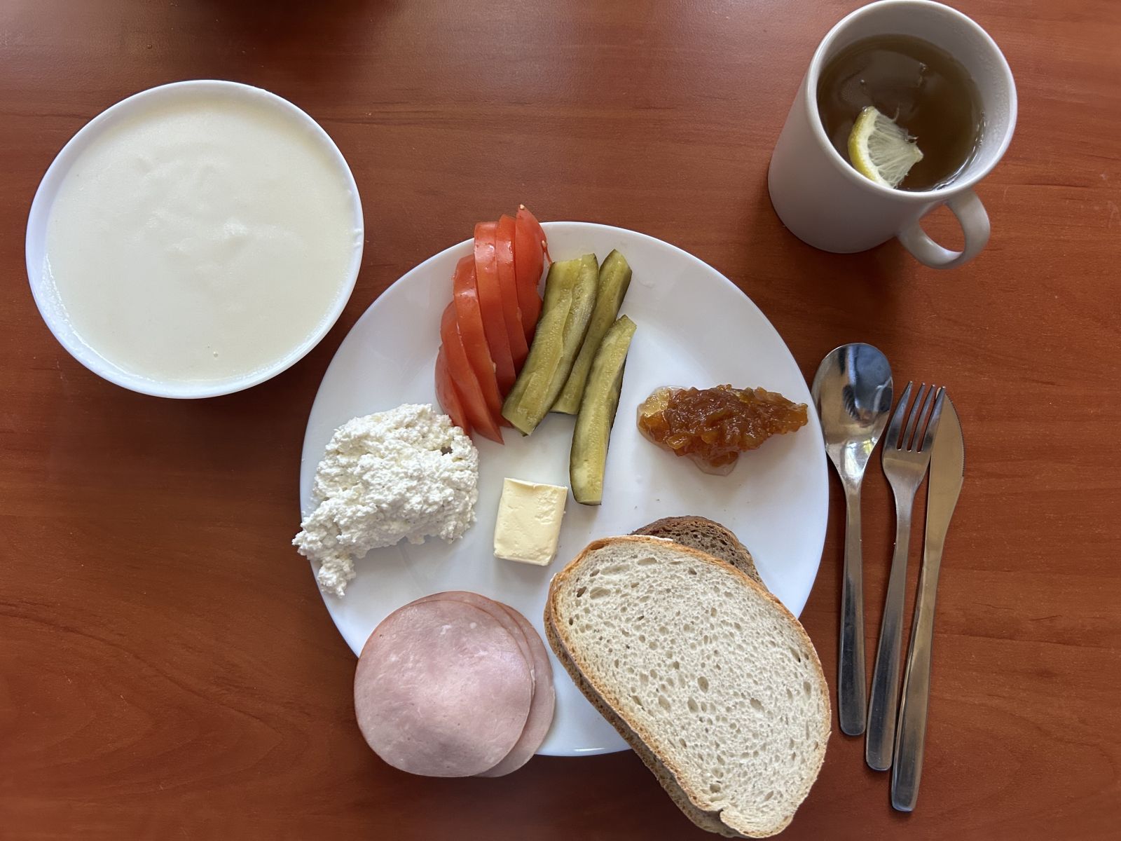 Kasza manna na mleku, chleb pszenny i żytni, pomidor, og&oacute;rek kiszony, wędlina, twar&oacute;g, dżem